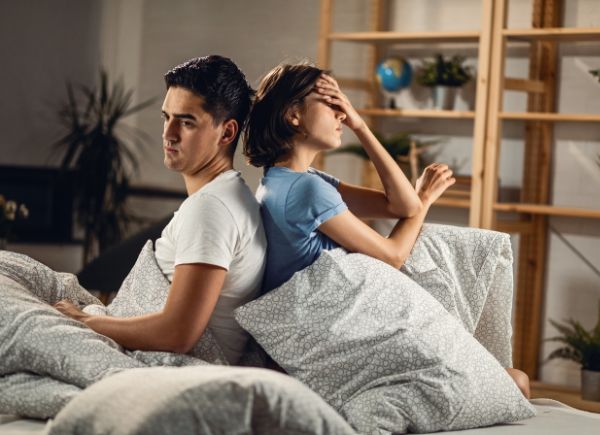 blog hero image. A couple sitting on a bed back to back, not talking to each other.